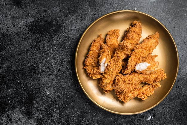 Pollo impanato strisce di filetto di petto di carne su un piatto Backgrund nero Vista dall'alto Spazio di copia