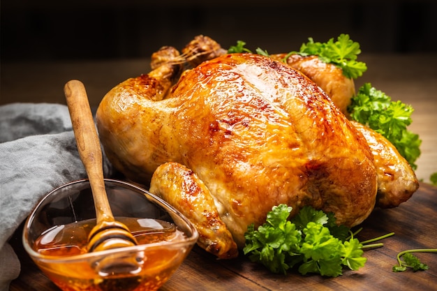 Pollo intero al forno con pelle croccante glassata con miele sopra e prezzemolo sul lato.