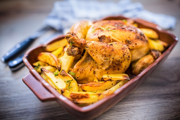 Pollo intero arrosto con patate in teglia. Cibo gustoso a casa sul bancone della cucina.