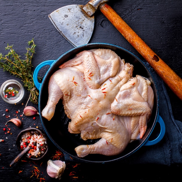 Pollo intero crudo con erbe e spezie su una padella