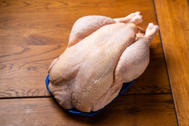 Pollo intero crudo su sfondo di legno Carcassa di pollo dal negozio