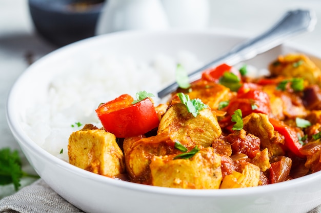 Pollo Jalfrezi con riso in ciotola bianca. Concetto di cucina indiana tradizionale.