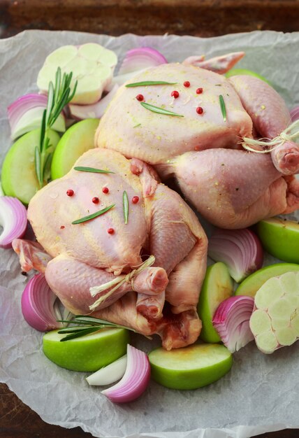 Pollo organico crudo due con mele verdi, cipolla rossa e rosmarino per cottura