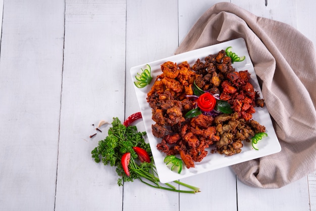 Pollo pakoda o pakoratre diversi gusti di pakora disposti in un piatto quadrato bianco