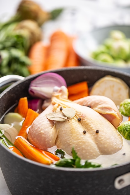 Pollo pronto da cucinare brodo con ortaggi a radice fresca e spezie.