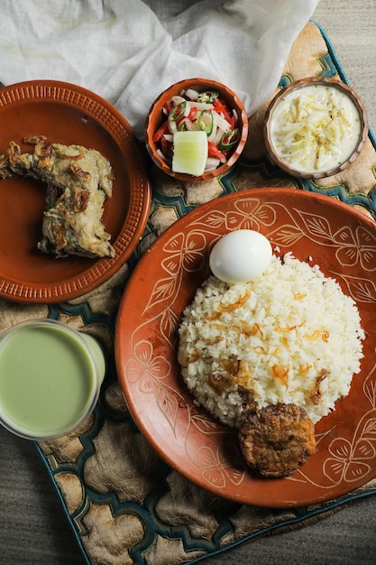 Pollo pulao biryani Morog Pulao Combo con insalata borhani e Chui Pitha servito in piatto isolato su tappetino vista dall'alto di cibo indiano e bangladeshi