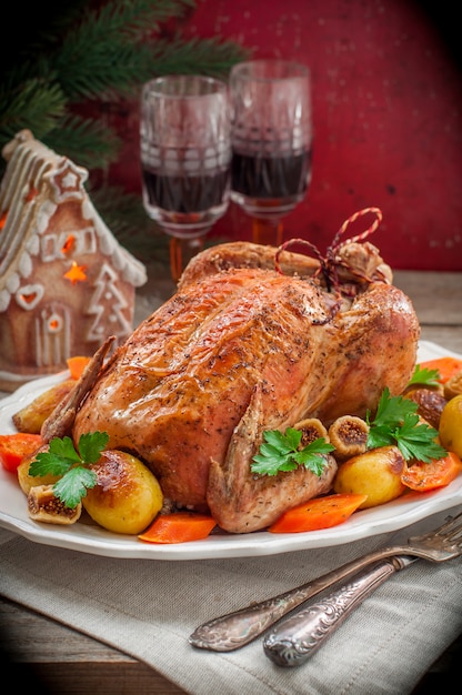 Pollo ripieno di Natale servito con patate, carote e fichi