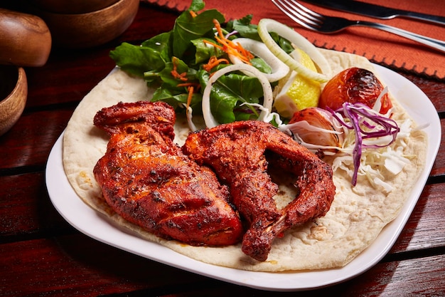 Pollo Tandoori alla griglia con insalata di pane e limone servito in un piatto isolato sulla vista laterale del tavolo del cibo del Medio Oriente