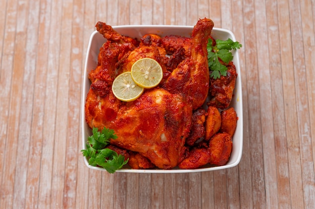 Pollo Tandoori piccante guarnito con foglia di coriandolo in ciotola bianca a forma quadrata