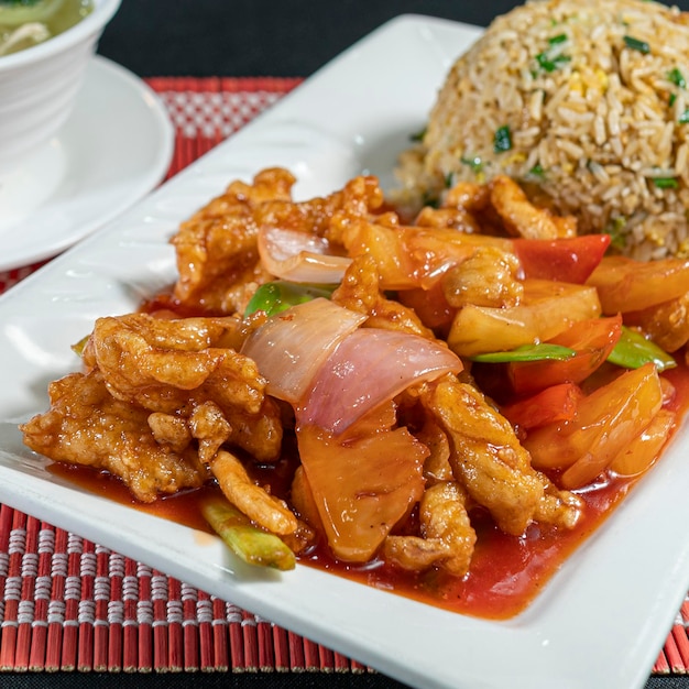 Pollo Tipakay (dolce) con riso chaufa e zuppa wantan. Cibo cinese peruviano