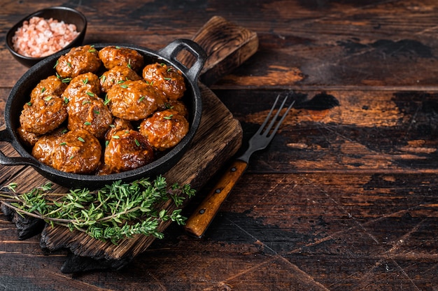 Polpette al sugo di carne bovina e suina al timo in padella rustica. Sfondo scuro. Vista dall'alto. Copia spazio.