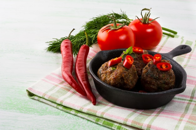 Polpette alla griglia servite con fette di peperoncino in padella di ghisa