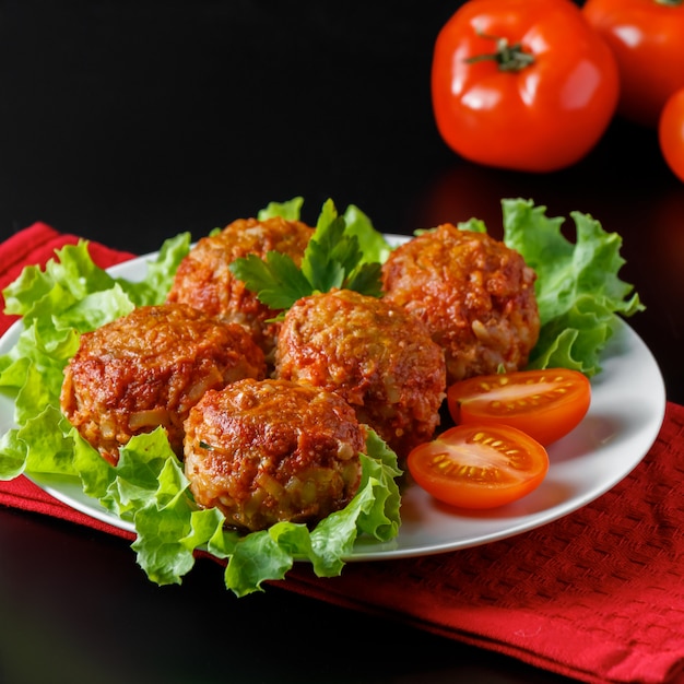 Polpette appetitose in salsa al pomodoro su uno spazio scuro. Piatto ad alto contenuto proteico.