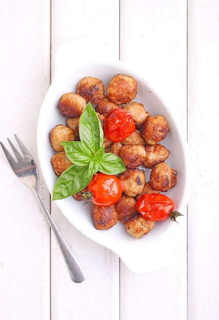 Polpette con pomodoro in un piatto bianco su uno sfondo bianco. messa a fuoco selettiva.