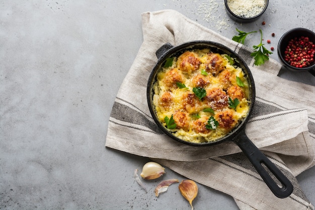 Polpette di carne con formaggio e salsa di panna in padella in ghisa su superficie grigia dell'annata