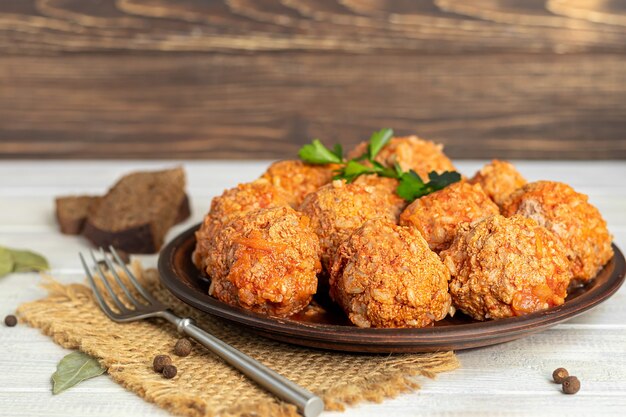 Polpette di carne su fondo chiaro con foglie di salvia e prezzemolo. Pranzo fatto in casa.