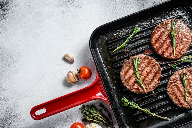 Polpette di hamburger di manzo che sfrigolano su una padella calda per barbecue. Vista dall'alto. Copia spazio