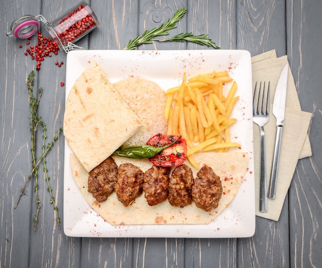 Polpette di vitello alla griglia con contorno di patate sul tavolo di legno