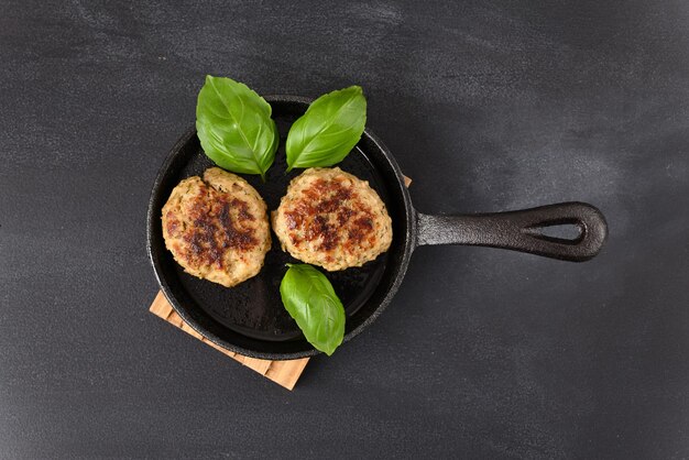 Polpette fritte calde con foglia di basilico in padella nera.