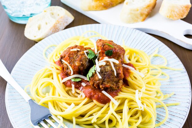 Polpette italiane fatte in casa guarnite con coriandolo e parmigiano su spaghetti per cena.