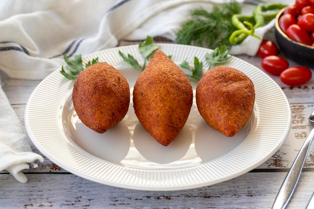 Polpette ripiene prelibatezze della cucina turca Kibbeh o icli kofte su pavimento di legno da vicino