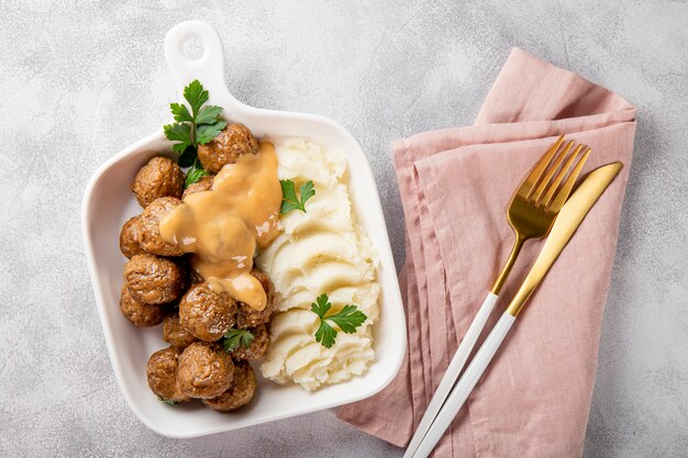 polpette svedesi tradizionali con salsa cremosa e purè di patate su sfondo grigio