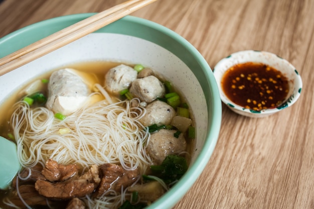 Polpettone di maiale con zuppa di noodle e tofu in una ciotola con bacchette e salsa