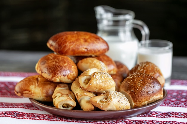 Polpettoni e panini dolci su una tavola con latte su fondo. Panini al forno con ripieno di carne.