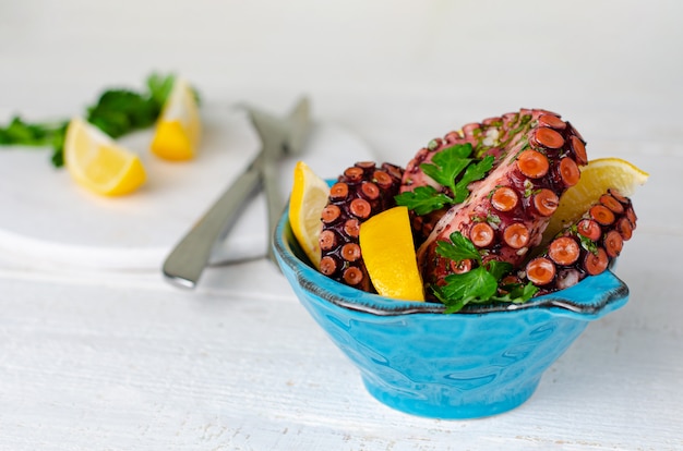 Polpo marinato con limone e prezzemolo in una ciotola blu