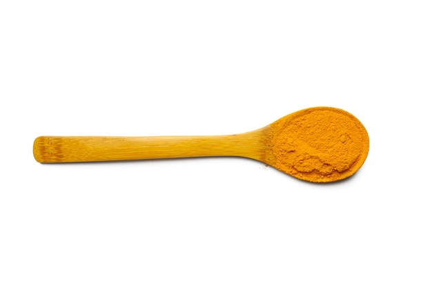 Polvere asciutta della curcuma e cucchiaio di legno su fondo bianco isolato Primo piano della curcuma arancio di colore della polvere Vista superiore