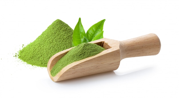 Polvere del tè verde di Matcha in mestolo e foglia di legno su bianco