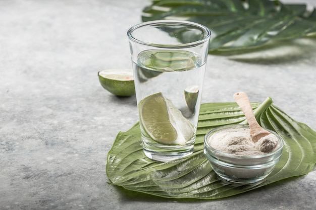 Polvere di collagene e bicchiere d'acqua con fetta di lime; Vitamina C . Gli integratori di collagene possono migliorare la salute della pelle riducendo rughe e secchezza.