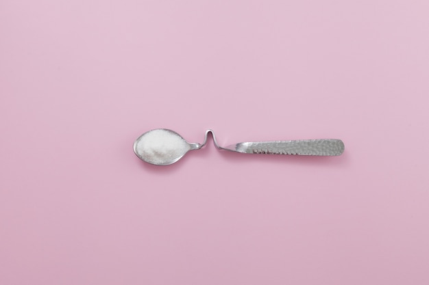 Polvere di collagene o proteine in cucchiaio d'argento su sfondo rosa. Integratore alimentare sano per la bellezza e la salute.