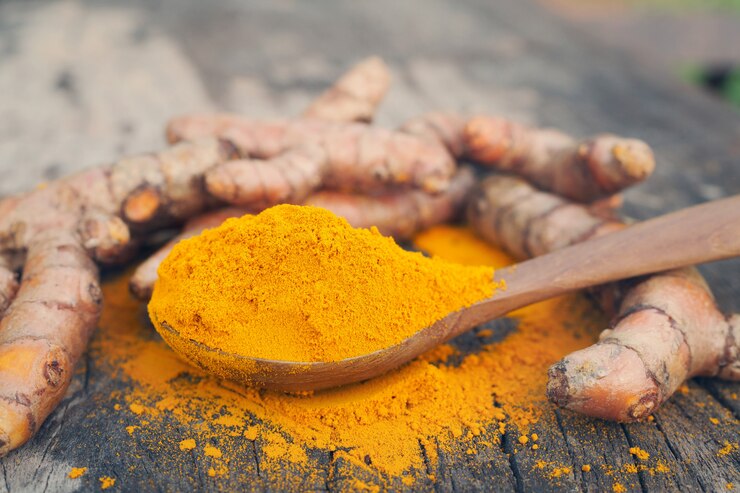 Polvere di curcuma e curcuma fresca in cucchiaio di legno sulla vecchia tavola di legno.