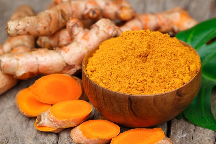 Polvere di curcuma in ciotole di legno su un tavolo di legno