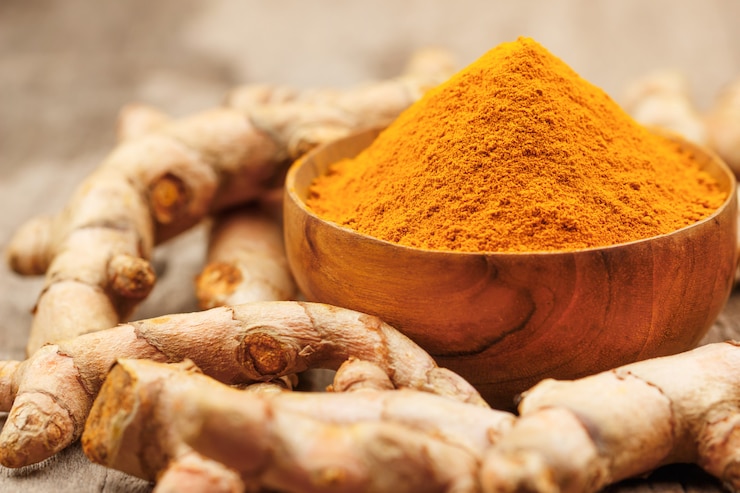 Polvere di curcuma in ciotole di legno su un tavolo di legno