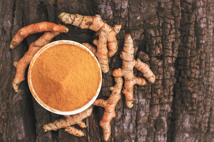 Polvere di curcuma in ciotole di legno su un tavolo di legno
