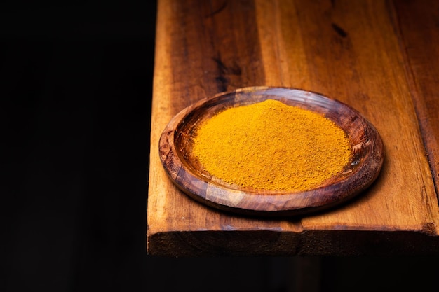 Polvere di curcuma in un cucchiaio di legno e una ciotola