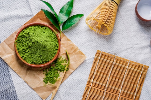 Polvere di tè verde con foglia in un piatto di ceramica sul tavolo, frusta giapponese fatta di bambù per la cerimonia del tè matcha