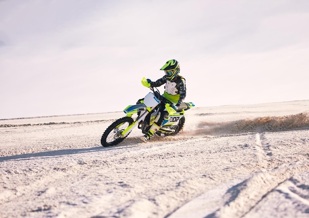 Polvere e velocità di motocicletta con un uomo sportivo che guida un veicolo nel deserto per l'avventura o l'adrenalina Libertà di moto e allenamento sulla sabbia con un atleta all'aperto in natura per la potenza o la competizione