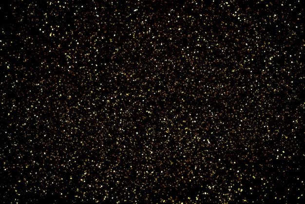 Polvere glitter oro scintillante su sfondo nero texture natale