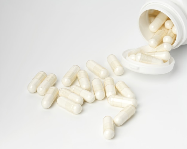 Polvere medica in capsule bianche su sfondo bianco. Pillole per il trattamento, integratori alimentari. sfondo bianco