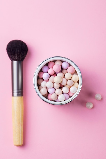 Polvere per trucco perlato con pennello su sfondo rosa pastello Vista dall'alto