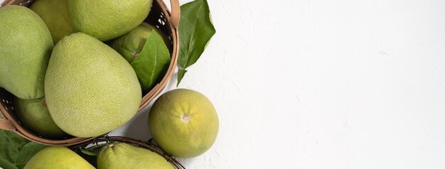 Pomelo fresco pummelo pompelmo shaddock su cemento bianco sullo sfondo nel cesto di bambù Autunno frutta stagionale vista dall'alto piatto laico colpo da tavolo