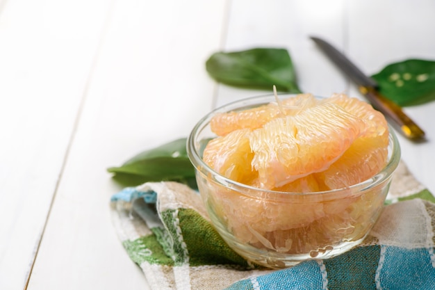 Pomelo o pompelmo pelati freschi in una ciotola di vetro su legno bianco