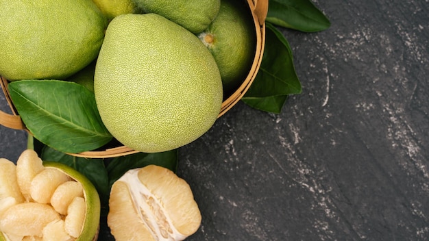 Pomelo pelato fresco pompelmo shaddock su sfondo scuro nel cesto di bambù Autunno frutta stagionale vista dall'alto piatto laici colpo da tavolo