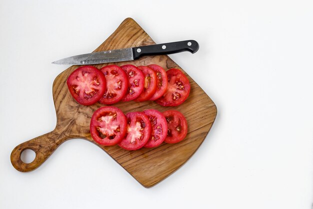 Pomodori a fette isolati su una tavola di legno su uno sfondo bianco, vista dall'alto, copia dello spazio