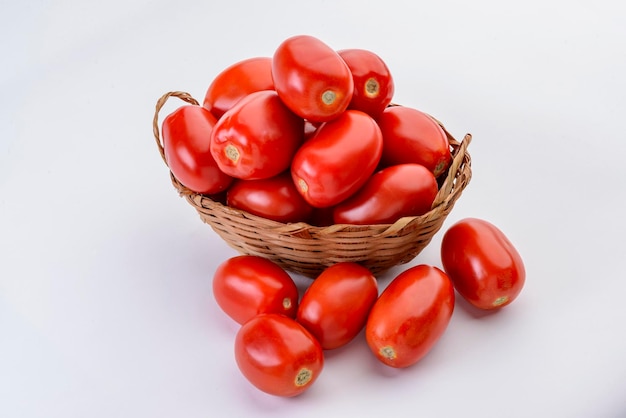 Pomodori all'interno del cesto di paglia isolati su sfondo bianco