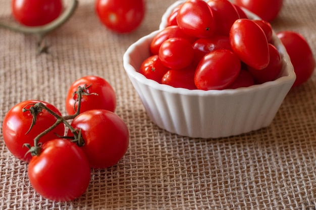 Pomodori all'interno di una ciotola bianca e su un tavolo di paglia