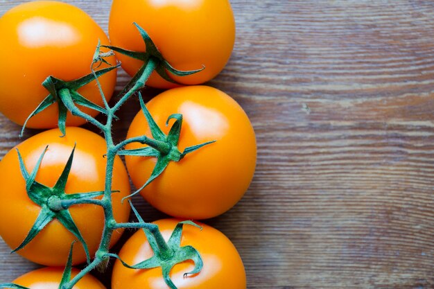 Pomodori arancioni succosi freschi sulla tavola di legno d'annata